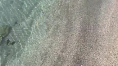 Sakin ve berrak dalgalı sakin kış plajı. Saf kumlu sahil kışın kristal berrak turkuaz denizle buluşur. Yumuşak dalgalarla huzurlu, minimalist doğa manzarası. Tenha bir kumsalda nefes kesen sakin bir kış sabahı..