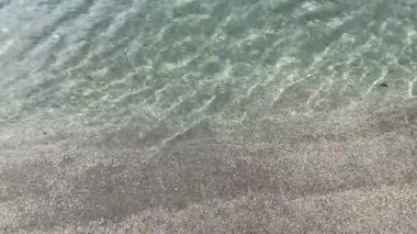 Sakin ve berrak dalgalı sakin kış plajı. Saf kumlu sahil kışın kristal berrak turkuaz denizle buluşur. Yumuşak dalgalarla huzurlu, minimalist doğa manzarası. Tenha bir kumsalda nefes kesen sakin bir kış sabahı..