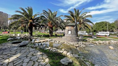 Atakoy, İstanbul, Türkiye.21 Şubat 2026.İstanbul, Türkiye 'nin Atakoy semtindeki Kazakistan Parkı' nın geniş açılı manzara manzarası, bereketli palmiye ağaçları, dekoratif ahşap bir yel değirmeni ve manzaralı kayalık bir dere manzarası.