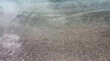 Çakıl taşlı sahilde kristal berrak su. Yüksek açılı sakin, şeffaf turkuaz deniz dalgaları kumlu sahilde dalgalanır. Yaz seyahati için huzurlu bir tropikal tatil geçmişi.