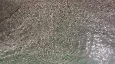 Çakıl taşlı sahilde kristal berrak su. Yüksek açılı sakin, şeffaf turkuaz deniz dalgaları kumlu sahilde dalgalanır. Yaz seyahati için huzurlu bir tropikal tatil geçmişi.