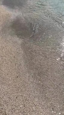 Çakıl taşlı sahilde kristal berrak su. Yüksek açılı sakin, şeffaf turkuaz deniz dalgaları kumlu sahilde dalgalanır. Yaz seyahati için huzurlu bir tropikal tatil geçmişi.