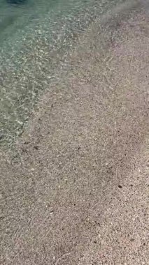 Çakıl taşlı sahilde kristal berrak su. Yüksek açılı sakin, şeffaf turkuaz deniz dalgaları kumlu sahilde dalgalanır. Yaz seyahati için huzurlu bir tropikal tatil geçmişi.