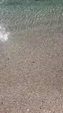 Çakıl taşlı sahilde kristal berrak su. Yüksek açılı sakin, şeffaf turkuaz deniz dalgaları kumlu sahilde dalgalanır. Yaz seyahati için huzurlu bir tropikal tatil geçmişi.