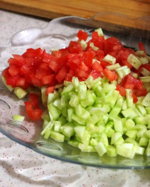 Akşam yemeği için salatalık ve domates salatası yapan kişi salata yapıyor.,