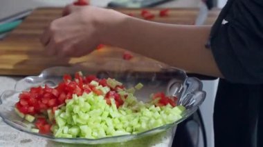 Akşam yemeği için salatalık ve domates salatası yapan kişi salata yapıyor.,