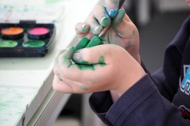 Çocuk suluboya ile oynuyor, çocuk yakın plan resim yapıyor.