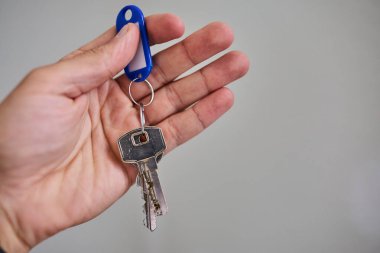 Apartman kapısının anahtarlarını elinde tutuyorsun. Ev, gayrimenkul, mülkiyet, taşınma, kira, güvenlik ve yeni başlangıçlar kavramı. Konut, sigorta ve mülkiyete ilişkin konular için uygun minimum ve temiz kompozisyon.