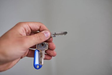 Apartman kapısının anahtarlarını elinde tutuyorsun. Ev, gayrimenkul, mülkiyet, taşınma, kira, güvenlik ve yeni başlangıçlar kavramı. Konut, sigorta ve mülkiyete ilişkin konular için uygun minimum ve temiz kompozisyon.