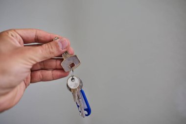 Apartman kapısının anahtarlarını elinde tutuyorsun. Ev, gayrimenkul, mülkiyet, taşınma, kira, güvenlik ve yeni başlangıçlar kavramı. Konut, sigorta ve mülkiyete ilişkin konular için uygun minimum ve temiz kompozisyon.