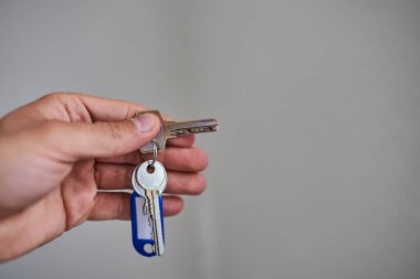 Apartman kapısının anahtarlarını elinde tutuyorsun. Ev, gayrimenkul, mülkiyet, taşınma, kira, güvenlik ve yeni başlangıçlar kavramı. Konut, sigorta ve mülkiyete ilişkin konular için uygun minimum ve temiz kompozisyon.