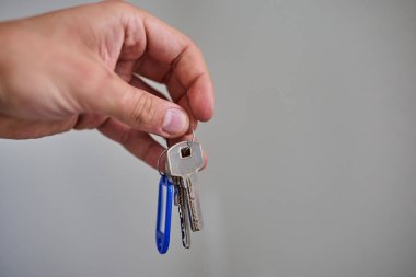 Apartman kapısının anahtarlarını elinde tutuyorsun. Ev, gayrimenkul, mülkiyet, taşınma, kira, güvenlik ve yeni başlangıçlar kavramı. Konut, sigorta ve mülkiyete ilişkin konular için uygun minimum ve temiz kompozisyon.