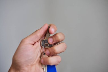 Apartman kapısının anahtarlarını elinde tutuyorsun. Ev, gayrimenkul, mülkiyet, taşınma, kira, güvenlik ve yeni başlangıçlar kavramı. Konut, sigorta ve mülkiyete ilişkin konular için uygun minimum ve temiz kompozisyon.