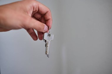 Apartman kapısının anahtarlarını elinde tutuyorsun. Ev, gayrimenkul, mülkiyet, taşınma, kira, güvenlik ve yeni başlangıçlar kavramı. Konut, sigorta ve mülkiyete ilişkin konular için uygun minimum ve temiz kompozisyon.