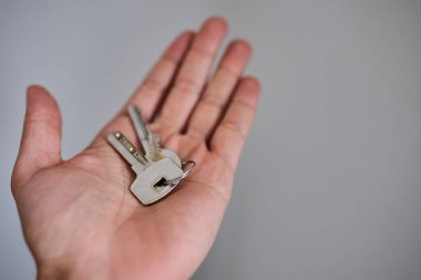 Apartman kapısının anahtarlarını elinde tutuyorsun. Ev, gayrimenkul, mülkiyet, taşınma, kira, güvenlik ve yeni başlangıçlar kavramı. Konut, sigorta ve mülkiyete ilişkin konular için uygun minimum ve temiz kompozisyon.