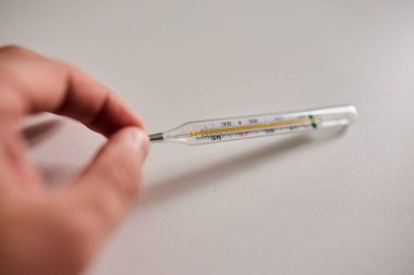 Bir elde tutulan dijital termometrenin yakın çekimi, vücut ısısını ölçmek için kullanılır. Sağlık, hastalık, ateş, tıbbi teşhis, evde tedavi ve sağlık izleme kavramı. Tıbbi ve sağlık için uygun temiz ve minimal bileşim