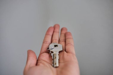 Apartman kapısının anahtarlarını elinde tutuyorsun. Ev, gayrimenkul, mülkiyet, taşınma, kira, güvenlik ve yeni başlangıçlar kavramı. Konut, sigorta ve mülkiyete ilişkin konular için uygun minimum ve temiz kompozisyon.