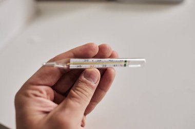 Bir elde tutulan dijital termometrenin yakın çekimi, vücut ısısını ölçmek için kullanılır. Sağlık, hastalık, ateş, tıbbi teşhis, evde tedavi ve sağlık izleme kavramı. Tıbbi ve sağlık için uygun temiz ve minimal bileşim