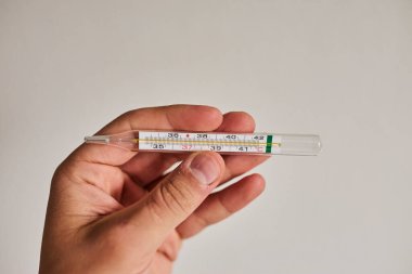 Bir elde tutulan dijital termometrenin yakın çekimi, vücut ısısını ölçmek için kullanılır. Sağlık, hastalık, ateş, tıbbi teşhis, evde tedavi ve sağlık izleme kavramı. Tıbbi ve sağlık için uygun temiz ve minimal bileşim