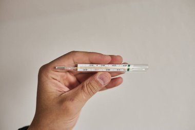 Bir elde tutulan dijital termometrenin yakın çekimi, vücut ısısını ölçmek için kullanılır. Sağlık, hastalık, ateş, tıbbi teşhis, evde tedavi ve sağlık izleme kavramı. Tıbbi ve sağlık için uygun temiz ve minimal bileşim