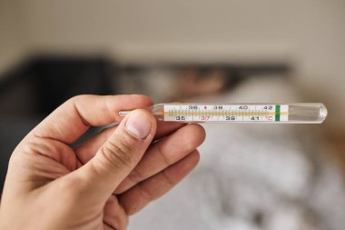 Bir elde tutulan dijital termometrenin yakın çekimi, vücut ısısını ölçmek için kullanılır. Sağlık, hastalık, ateş, tıbbi teşhis, evde tedavi ve sağlık izleme kavramı. Tıbbi ve sağlık için uygun temiz ve minimal bileşim