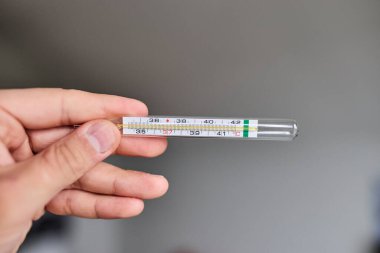 Bir elde tutulan dijital termometrenin yakın çekimi, vücut ısısını ölçmek için kullanılır. Sağlık, hastalık, ateş, tıbbi teşhis, evde tedavi ve sağlık izleme kavramı. Tıbbi ve sağlık için uygun temiz ve minimal bileşim