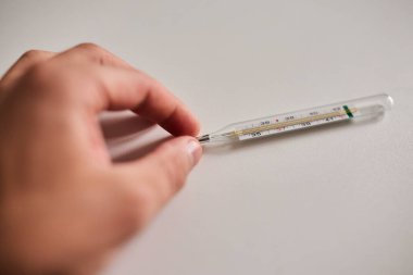 Bir elde tutulan dijital termometrenin yakın çekimi, vücut ısısını ölçmek için kullanılır. Sağlık, hastalık, ateş, tıbbi teşhis, evde tedavi ve sağlık izleme kavramı. Tıbbi ve sağlık için uygun temiz ve minimal bileşim