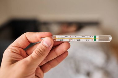 Bir elde tutulan dijital termometrenin yakın çekimi, vücut ısısını ölçmek için kullanılır. Sağlık, hastalık, ateş, tıbbi teşhis, evde tedavi ve sağlık izleme kavramı. Tıbbi ve sağlık için uygun temiz ve minimal bileşim