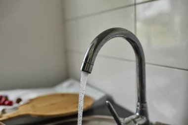 Mutfak musluğundan akan temiz suyun yakın çekimi. Temiz su, ev kullanımı, hijyen, sürdürülebilirlik, günlük rutin su ve su kavramı