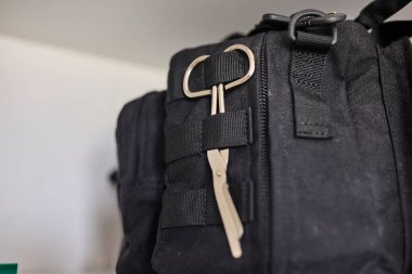 Keskin uçlu tıbbi makas taktiksel bir keseye bağlı. İlk yardım, acil müdahale, tıbbi ekipman, güvenlik ve hazırlık kavramı. Sağlık, askeri, taktik ve acil servis temaları için uygundur.