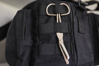 Keskin uçlu tıbbi makas taktiksel bir keseye bağlı. İlk yardım, acil müdahale, tıbbi ekipman, güvenlik ve hazırlık kavramı. Sağlık, askeri, taktik ve acil servis temaları için uygundur.