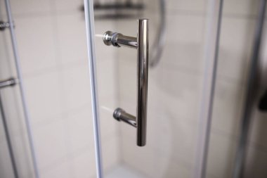 Ucuz bir cam kapıya monte edilmiş basit metal bir kapı kolu. Bütçe içeriği kavramı, asgari tasarım, ofis veya konut giriş ayrıntıları.