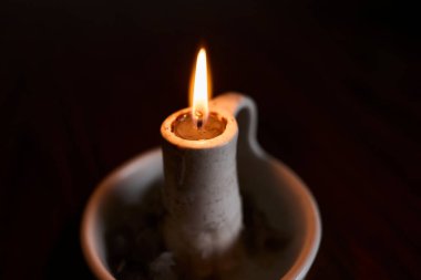 Mum tutacağında yanan tek bir mum sıcak ve sakin bir atmosfer yaratır. Rahatlama, meditasyon, maneviyat ve rahat iç aydınlatma kavramı.