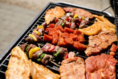 Barbekü ızgarasında cızırdayan bir sürü et. Açık hava yemekleri, yaz barbeküsü, ızgara ve lezzetli yemekler..