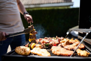 Barbekü ızgarasında cızırdayan bir sürü et. Açık hava yemekleri, yaz barbeküsü, ızgara ve lezzetli yemekler..