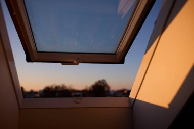 Tavana monte edilmiş bir çatı penceresi doğal ışığın boşluğa girmesine olanak sağlıyor. Görüntü modern mimariyi, iç tasarımı ve parlak yaşam alanlarını temsil eder. Doğal ışıklandırma kavramı, ev dekorasyonu, çağdaş tasarım ve konforlu.