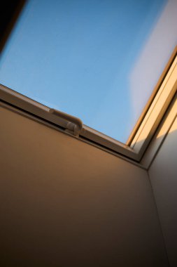 Tavana monte edilmiş bir çatı penceresi doğal ışığın boşluğa girmesine olanak sağlıyor. Görüntü modern mimariyi, iç tasarımı ve parlak yaşam alanlarını temsil eder. Doğal ışıklandırma kavramı, ev dekorasyonu, çağdaş tasarım ve konforlu.