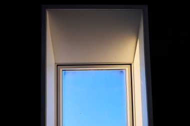 Tavana monte edilmiş bir çatı penceresi doğal ışığın boşluğa girmesine olanak sağlıyor. Görüntü modern mimariyi, iç tasarımı ve parlak yaşam alanlarını temsil eder. Doğal ışıklandırma kavramı, ev dekorasyonu, çağdaş tasarım ve konforlu.