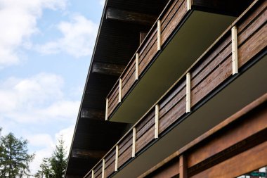 Geleneksel İsviçre dağ evi tarzı otel, yaz mevsiminde gün ışığında görkemli dağların ve huzurlu bir alp gölünün zeminine karşı ele geçirildi. Görüntü seyahat, konukseverlik ve İsviçre Alplerinin doğal güzelliğini temsil ediyor.