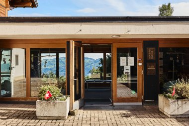 Geleneksel İsviçre dağ evi tarzı otel, yaz mevsiminde gün ışığında görkemli dağların ve huzurlu bir alp gölünün zeminine karşı ele geçirildi. Görüntü seyahat, konukseverlik ve İsviçre Alplerinin doğal güzelliğini temsil ediyor.