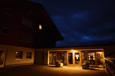 Yaz aylarında dağlarda çekilen geleneksel İsviçre dağ evi tarzı otel, sıcak akşam ışığında ele geçirildi. Görüntü konukseverliği, seyahati, dağ manzarasını ve sıcacık dağ mimarisini temsil ediyor. Yaz tatili kavramı, turizm, otel konaklama