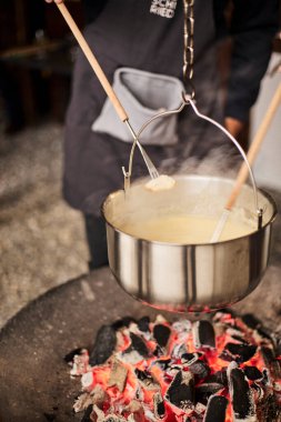 Geleneksel İsviçre peyniri fondüsü sıcak ve rahat bir ortamda hazırlanıyor. Sahne, otantik İsviçre mutfak kültürü, bölgesel gastronomi ve geleneksel bir yemek deneyimini yansıtıyor. Miras mutfağı, konukseverlik ve konukseverlik kavramları için ideal.