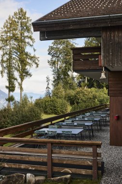 Yazın İsviçre 'deki Niesen Dağı manzaralı sandalyeli yemek masaları. Sahne, rahat bir alp atmosferi, açık havada konukseverlik ve manzaralı dağ titreşimleri taşır. Seyahat, boş zaman, yemek ve yemek kavramları için uygun.