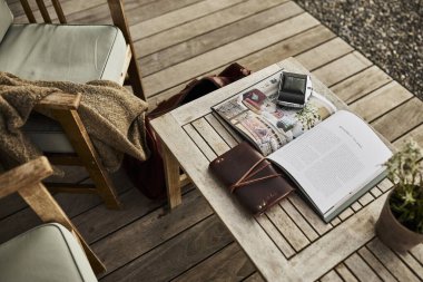 İsviçre 'de bir yaz akşamı manzaralı dağ manzaralı bir terasta sandalye ve masa. Sandalyede sıcak bir eşarp, deri bir seyahat çantası, bir defter ve masanın üzerinde Edelweiss çiçekleri olan bir kamera var. Sahne rahatlatıcı.