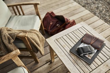 İsviçre 'de bir yaz akşamı manzaralı dağ manzaralı bir terasta sandalye ve masa. Sandalyede sıcak bir eşarp, deri bir seyahat çantası, bir defter ve masanın üzerinde Edelweiss çiçekleri olan bir kamera var. Sahne rahatlatıcı.