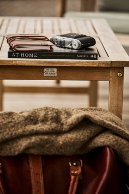 İsviçre 'de bir yaz akşamı manzaralı dağ manzaralı bir terasta sandalye ve masa. Sandalyede sıcak bir eşarp, deri bir seyahat çantası, bir defter ve masanın üzerinde Edelweiss çiçekleri olan bir kamera var. Sahne rahatlatıcı.