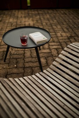 Huzurlu bir İsviçre yüksek irtifa atmosferinde, manzaralı bir dağ manzaralı, rahatlatıcı bir sandalyenin yanına bir kitap ve bir fincan çay yerleştirilir. Sahne sakinliği, yavaş yaşamı ve doğayla çevrili rahat bir dağlık yaşam tarzını yansıtıyor. Konseptler için uygun