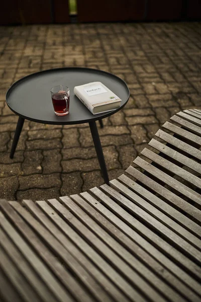 Huzurlu bir İsviçre yüksek irtifa atmosferinde, manzaralı bir dağ manzaralı, rahatlatıcı bir sandalyenin yanına bir kitap ve bir fincan çay yerleştirilir. Sahne sakinliği, yavaş yaşamı ve doğayla çevrili rahat bir dağlık yaşam tarzını yansıtıyor. Konseptler için uygun