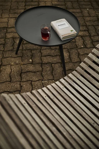 Huzurlu bir İsviçre yüksek irtifa atmosferinde, manzaralı bir dağ manzaralı, rahatlatıcı bir sandalyenin yanına bir kitap ve bir fincan çay yerleştirilir. Sahne sakinliği, yavaş yaşamı ve doğayla çevrili rahat bir dağlık yaşam tarzını yansıtıyor. Konseptler için uygun