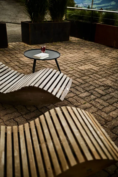 Huzurlu bir İsviçre yüksek irtifa atmosferinde, manzaralı bir dağ manzaralı, rahatlatıcı bir sandalyenin yanına bir kitap ve bir fincan çay yerleştirilir. Sahne sakinliği, yavaş yaşamı ve doğayla çevrili rahat bir dağlık yaşam tarzını yansıtıyor. Konseptler için uygun